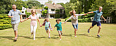 Family holding hands and running in grass