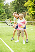 Father teaching son to play tennis