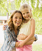 Mother and daughter hugging outdoors