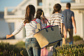 Girl with beach bag following family
