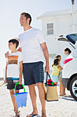 Father and son holding beach gear by car