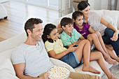 Family watching TV on sofa in living room