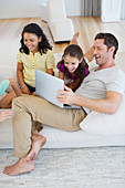 Father and daughters using laptop on sofa