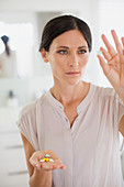 Woman examining pills in bathroom