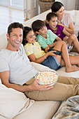 Family watching TV on sofa in living room