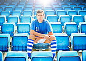 Soccer player sitting in empty stadium