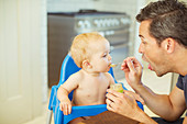 Father feeding baby in high chair