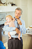 Father holding baby and eating breakfast