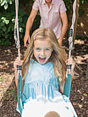 Father pushing daughter in swing