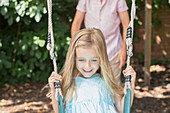 Father pushing daughter on swing
