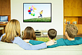 Family watching television in living room