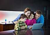 Family using laptop together in kitchen