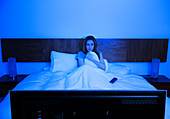 Woman watching television in bed