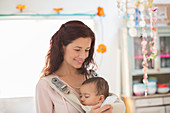 Mother holding baby girl in kitchen