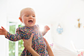 Mother holding baby girl in living room