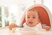 Baby boy eating in high chair