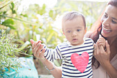 Mother helping baby boy walk outdoors