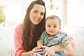 Mother holding baby boy on sofa