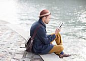 Man using digital tablet along river