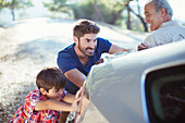 Multi-generation men pushing car