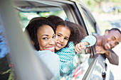 Happy family leaning out car windows