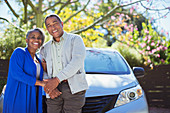 Happy senior couple leaning on car