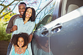 Portrait of happy family outside car