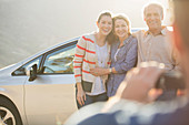 Man photographing family outside car