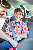 Father fastening seat belt for boy