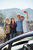 Family taking self-portrait outside car