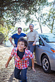 Happy multi-generation men outside car