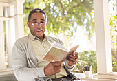 Smiling senior man reading book on porch