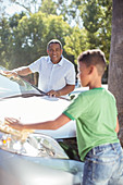 Grandfather and grandson washing car