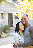 Smiling couple hugging outside house