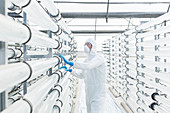 Engineer in clean suit examining pipes