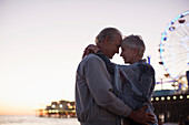 Senior couple hugging on beach at sunset