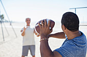 Senior men playing football on beach