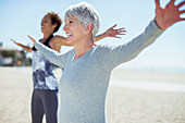 Senior women stretching arms on beach