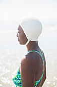Pensive woman in bathing suit and cap