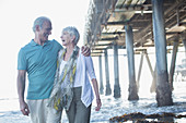 Senior couple laughing near pier at beach