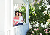 Smiling mother and daughter on porch