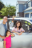 Smiling family at car in driveway