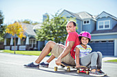 Father and daughter sitting on skateboard