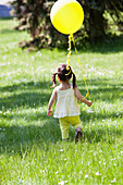 Girl carrying balloon in backyard