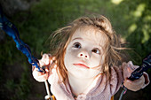 Baby girl sitting on swing outdoors