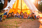 Children smiling in teepee at campsite