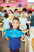 Student holding painted fish in classroom