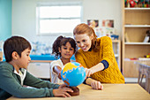 Students and teacher examining globe