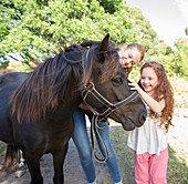 Mother and daughter petting horse