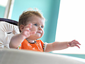 Baby girl reaching out from arm chair